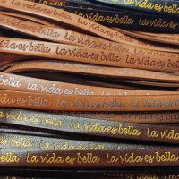 Buy Leather Cord Flat Leather with Text Embossed La Vida Es Bella Embossed - 10 mm  at wholesale prices