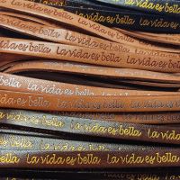 Buy Leer  Tekst Leer La Vida Es Bella Gegraveerd - 10mm  at wholesale prices