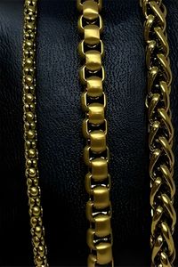 three gold chains displayed on a black textured background