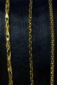 three gold chains displayed on a black textured background