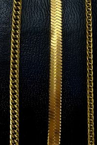 three gold chains displayed on a black textured background