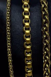 three gold chains displayed on a black textured background